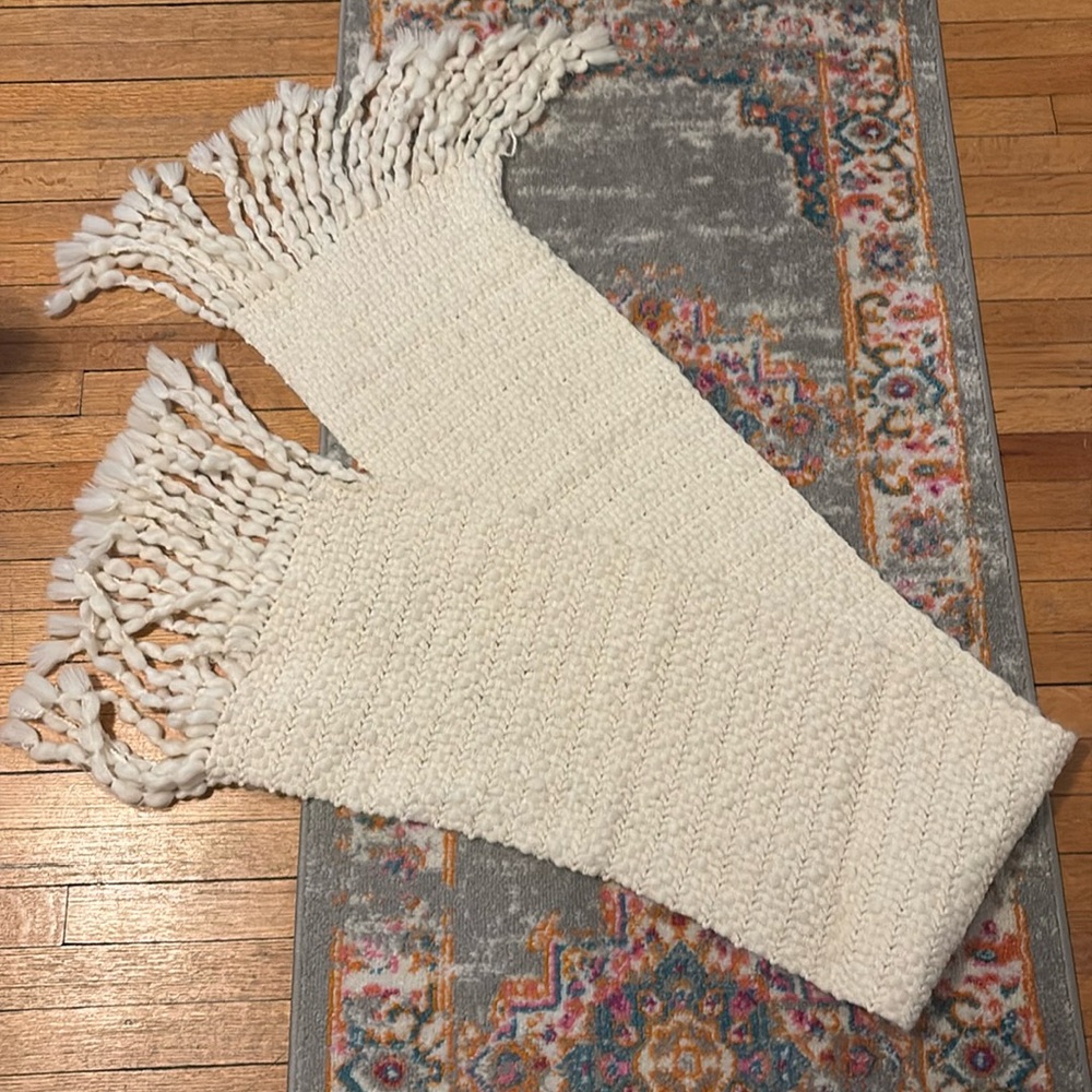 Cream colored, fringed bulky scarf.